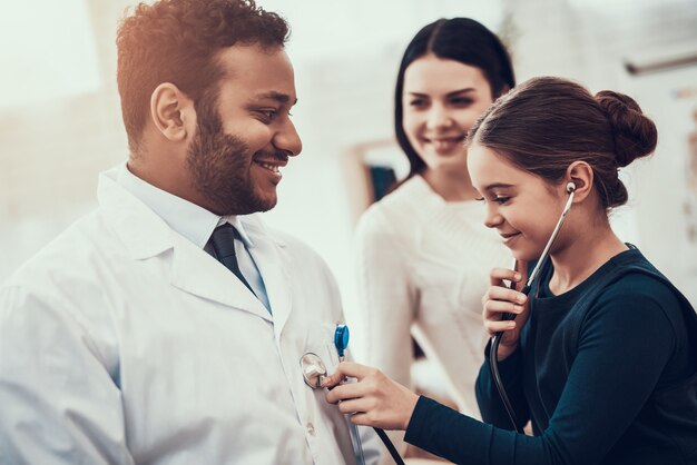 Little girl is using stethoscope on doctor.