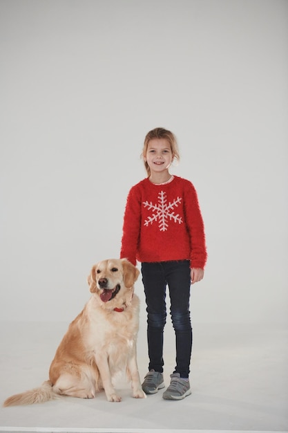 Little girl is with cute Golden retriever in the studio against white background