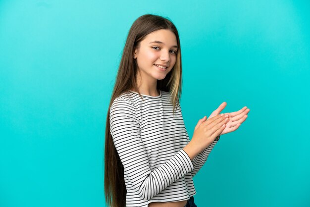 Little girl over isolated blue background applauding