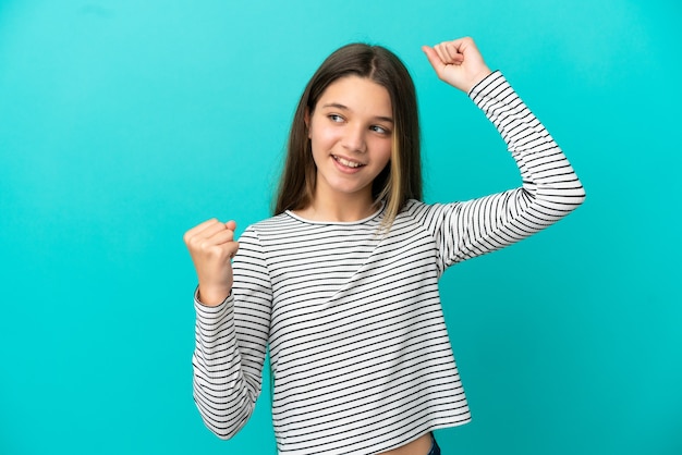 Little girl over isolated blue background celebrating a victory