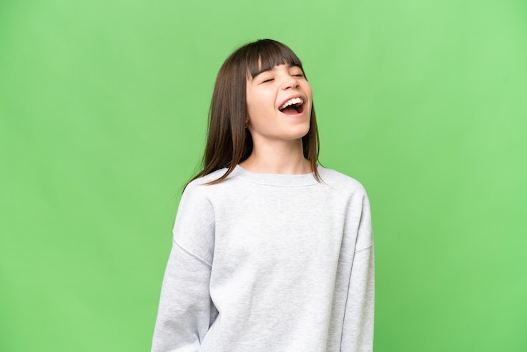 Photo 孤立した緑色の鍵の背景で笑う小さな女の子