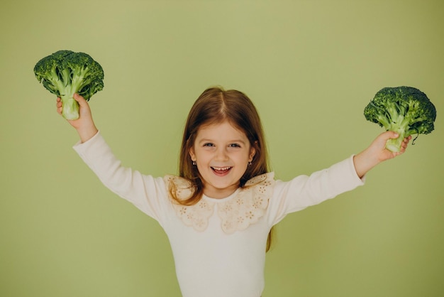 Little girl isolated holding green raw broccoli