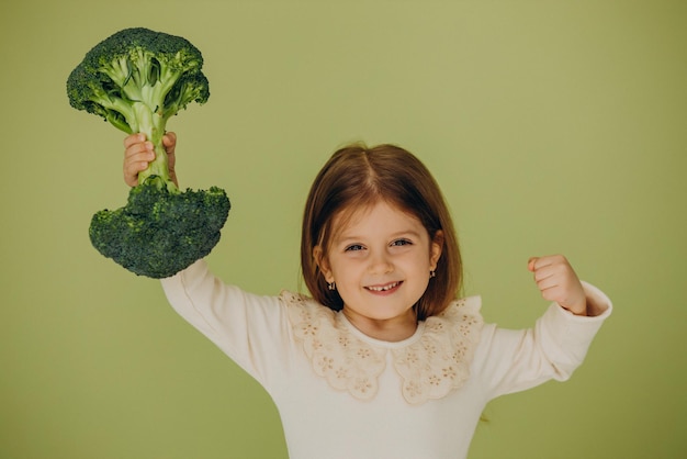 Little girl isolated holding green raw broccoli