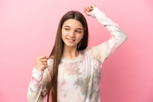 Little girl over isolated pink background celebrating a victory