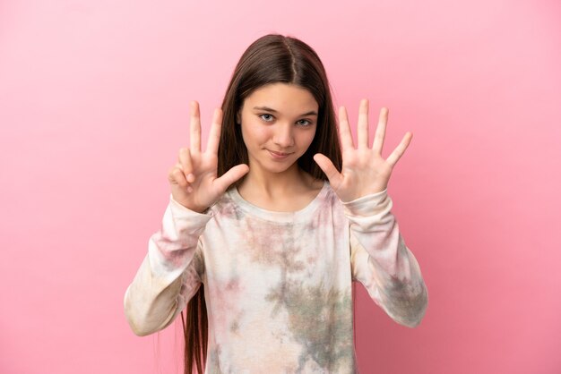 Little girl over isolated pink background counting eight with fingers