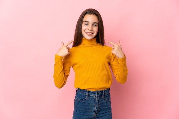 Little girl isolated on pink background giving a thumbs up gesture