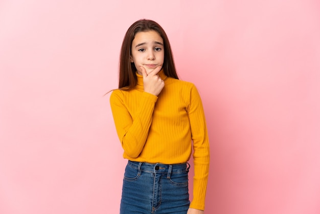 Little girl isolated on pink background having doubts