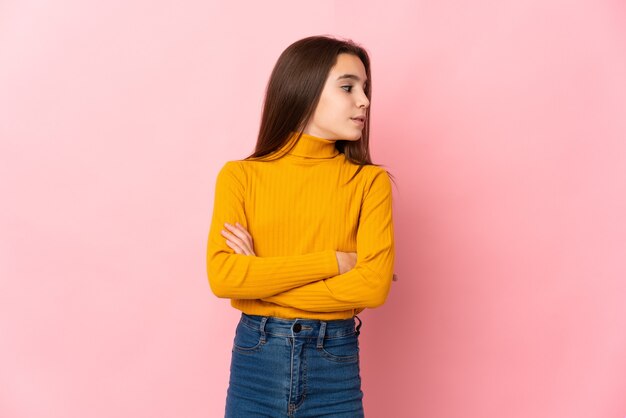 Little girl isolated on pink background keeping the arms crossed