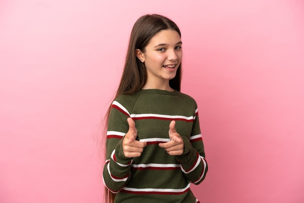 Little girl over isolated pink background pointing to the front and smiling