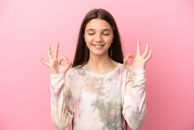 Little girl over isolated pink surface in zen pose