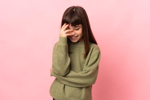 Little girl isolated on pink wall laughing