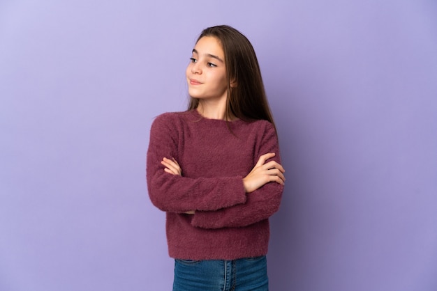 Little girl isolated on purple background looking to the side