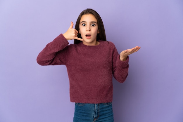 Little girl isolated on purple background making phone gesture and doubting