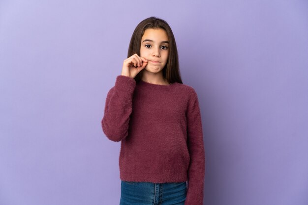 Маленькая девочка, изолированные на фиолетовом фоне, показывая знак жеста молчания