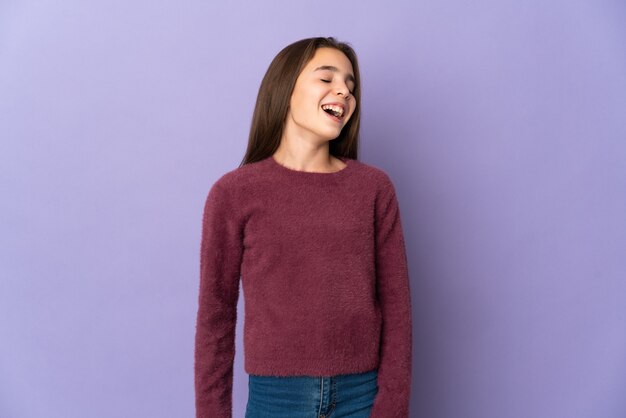 Little girl isolated on purple wall laughing