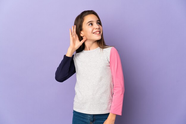 Little girl isolated on purple wall thinking an idea