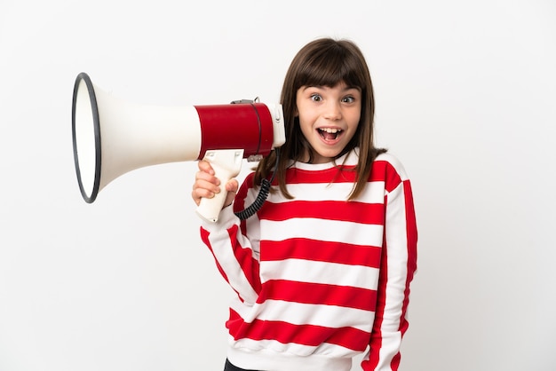 Little girl isolated on white background holding a megaphone and with surprise expression