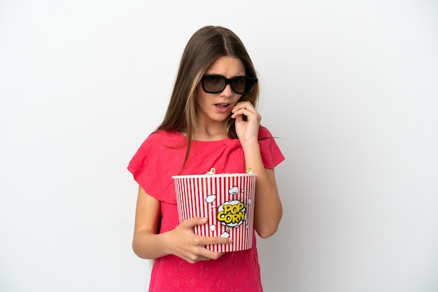 Маленькая девочка на изолированном белом фоне в 3d-очках и держит большое ведро попкорна