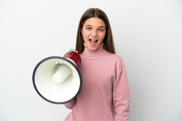 Little girl over isolated white surface holding a megaphone and with surprise expression