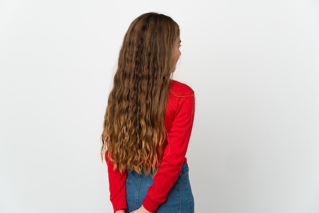 Little girl over isolated white wall in back position and looking back