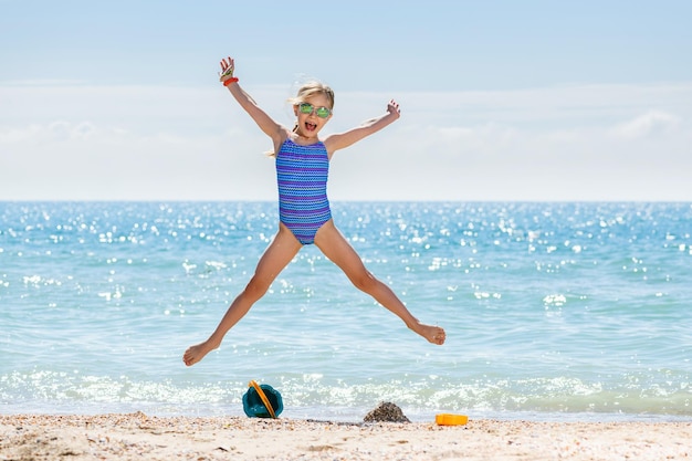 Маленькая девочка прыгает, как звезда на пляже
