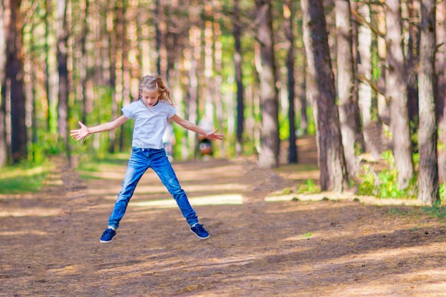 Little girl jumping outdoors in the forest On the background of trees