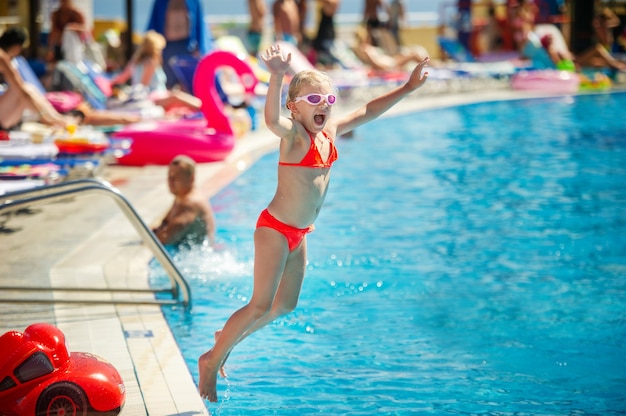 Una bambina salta in piscina al parco acquatico durante le vacanze estive.