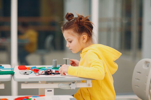 技術的なおもちゃをチェックする小さな女の子の子供子コンストラクタ。 ChildrenRoboticsコンストラクターがロボットを組み立てます。