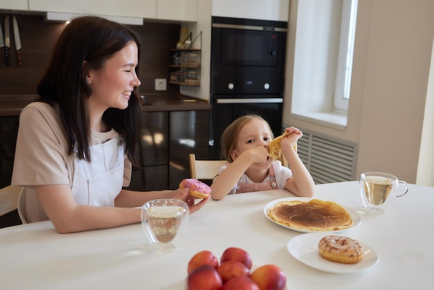 Little girl in the kitchen eats pancakes