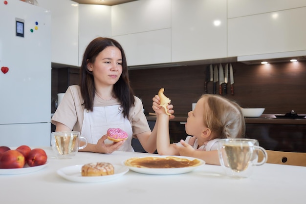 Little girl in the kitchen eats pancakes