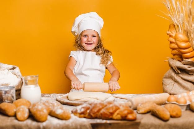 Little girl kneading dough at table