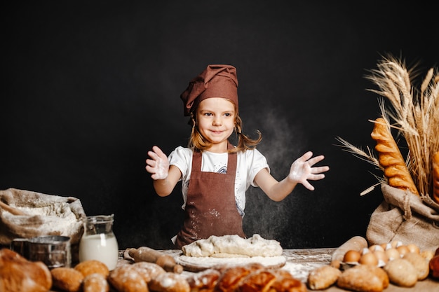 Photo little girl kneading dough at table