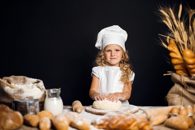 Little girl kneading dough at table