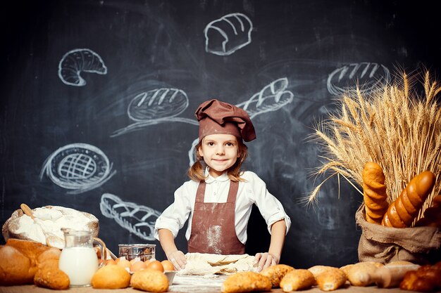 Little girl kneading dough at table