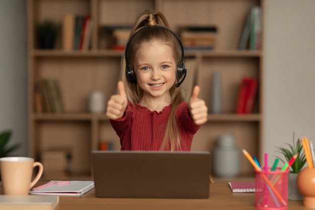 Little girl at laptop gesturing like approving elearning at home