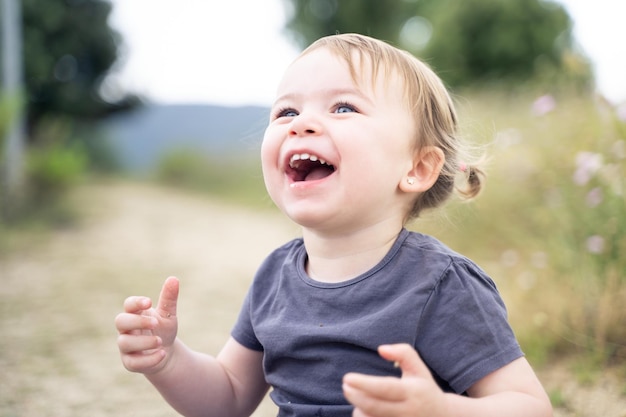 Little girl laughing with standing next to a rural path