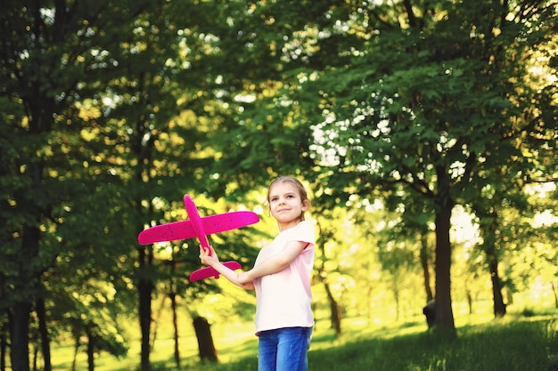 Little girl launches a toy plane into the air in the park