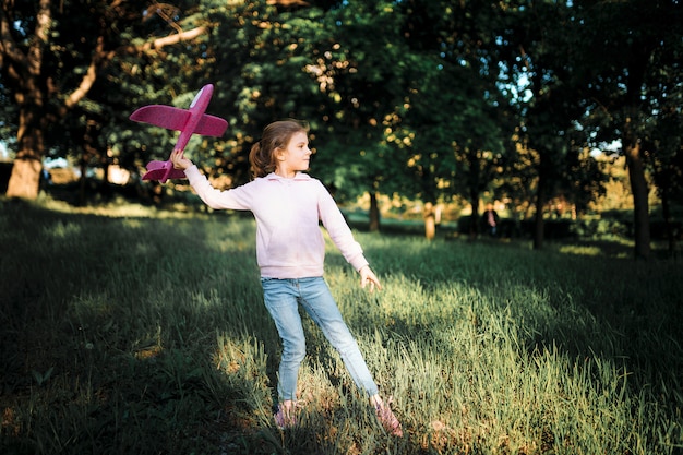 Little girl launches a toy plane into the air in the park