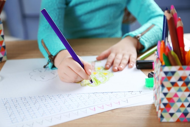 Little girl learning to draw at the table