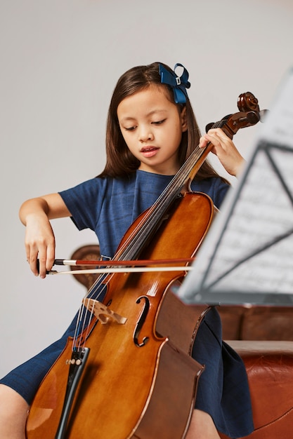 Маленькая девочка учится играть на виолончели