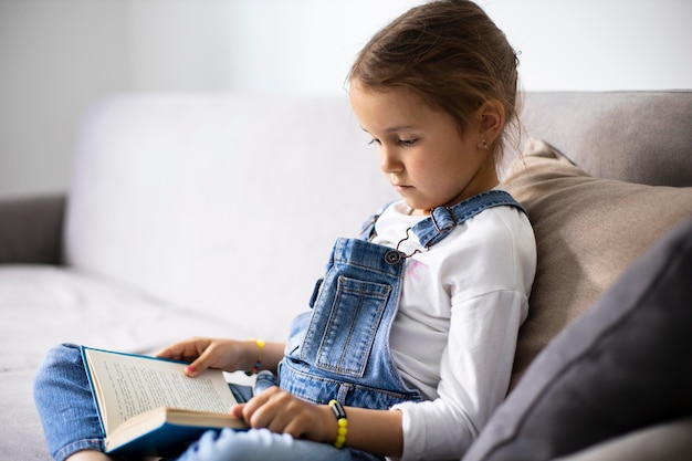 Foto bambina che impara a leggere da un libro