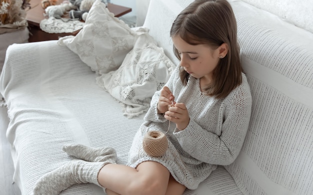 Little girl learning to knit, home leisure and needlework concept.