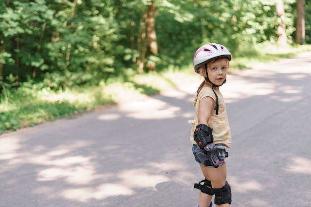 Little girl learning to roller skate. baby in protective sportswear