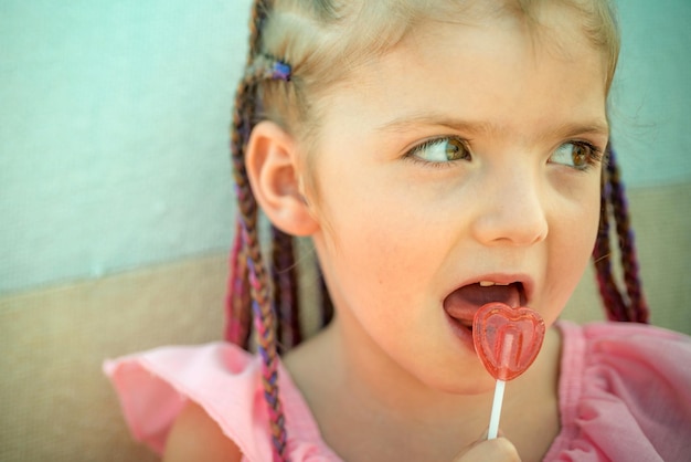 Little girl lick lollipop funny kids emotions outdoor close up portrait of a cute little child playi