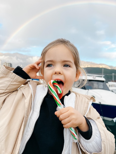 Premium Photo Little Girl Licks A Lollipop Against The Backdrop Of A Premium Photo Little Girl Licks A Lollipop Against The Backdrop Of A