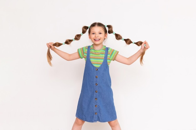 The little girl lifts her braids of hair up and smiles broadly Hairstyles for little girls White insulated background