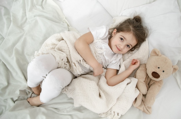 Little girl in light pajamas on the bed