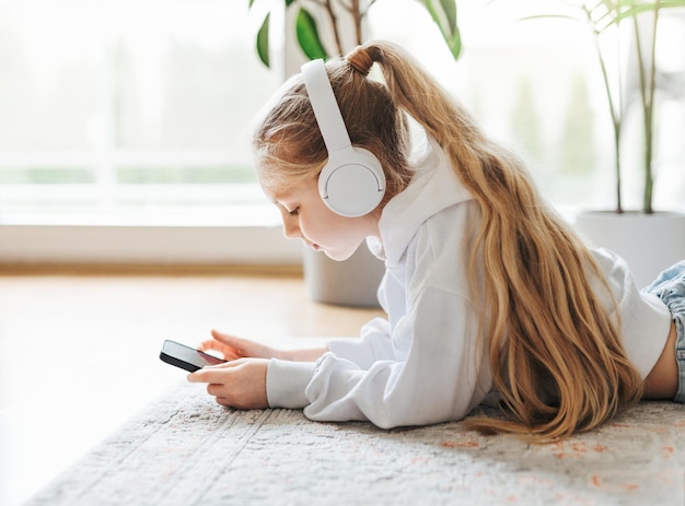 Little girl listening music lying on the floor