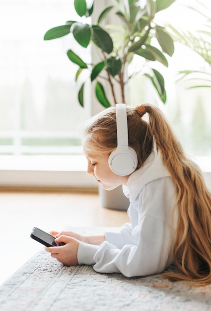 Little girl listening music lying on the floor