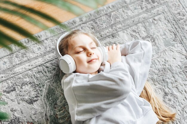 Little girl listening music lying on the floor